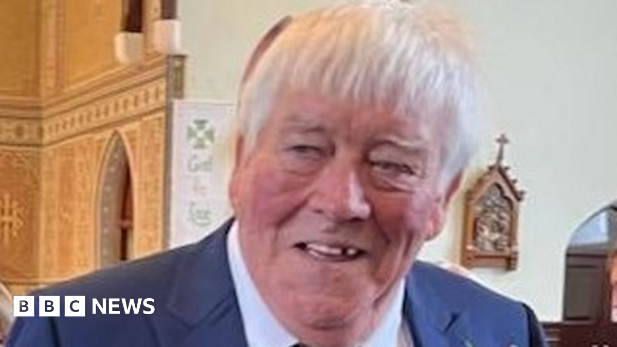 Prime Minister Mark Carney, wearing a black suit jacket, and a white button-up shirt leans his chin on his hands. He has short grey and black hair and is looking away from the camera.