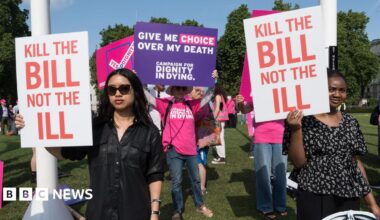People holding signs saying 'kill the bill not the ill' and 'give me choice over my death' stand protesting outdoors in Parliament Square in early June 2025.