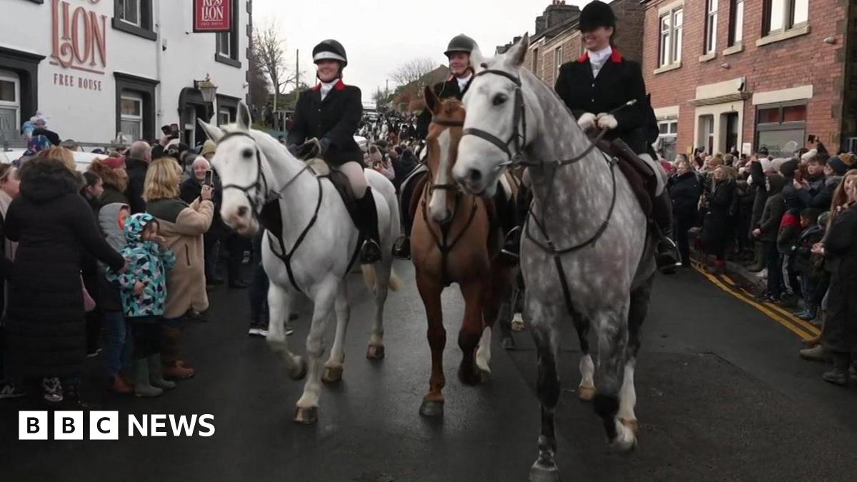 Riders with their hard hats and hunting outfits from The Holcombe Harriers hunt ride through the streets of  Wheelton, Lancashire opposdite the RTed Lion Inn.