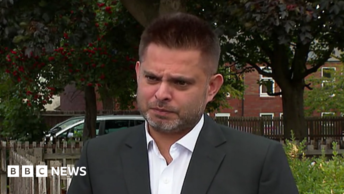 Waseem Zaffar a man in a black blazer and white shirt is looking at the camera with a stern expression
