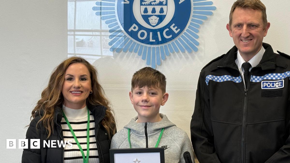 A woman, a boy and a man dressed in a police uniform are smiling at the camera