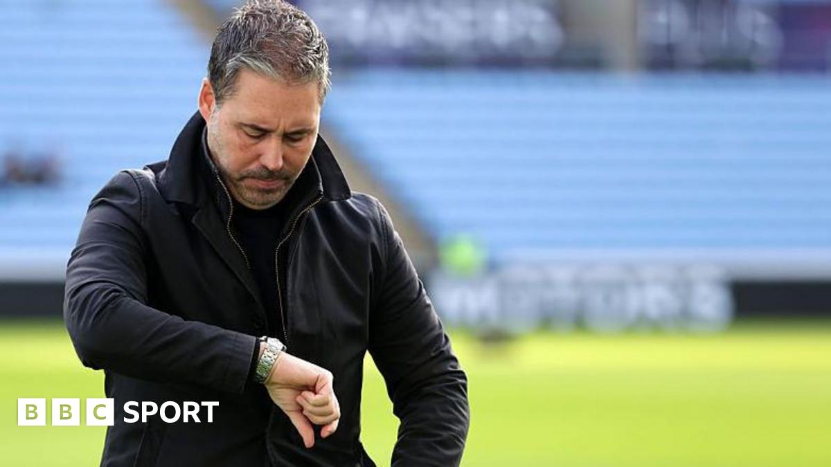 Marti Cifuentes looks down at his watch while preparing for a game as Leicester City manager