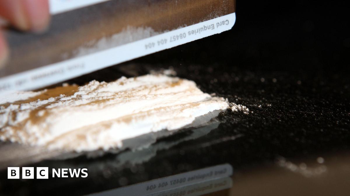 A person cutting up cocaine - only their hand can be seen, as well as the drug