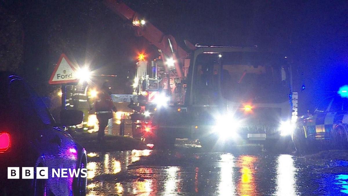 Lorry being removed from water by crane