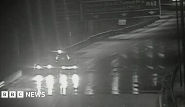 Black and white image shows flooding on surface of the M60 which has led to the motorway being closed so there is no traffic except for one vehicle on the hard shoulder.