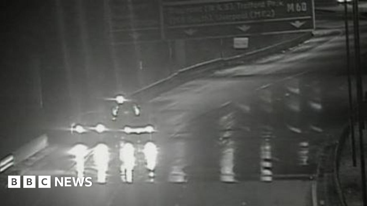 Black and white image shows flooding on surface of the M60 which has led to the motorway being closed so there is no traffic except for one vehicle on the hard shoulder.