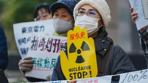 Getty Images A woman in a face mask holding an anti-nuclear power sign.