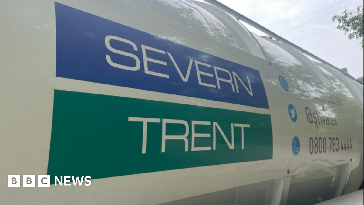 A silver mixer tap with water flowing from it. The hot and cold taps are blurred in the background.