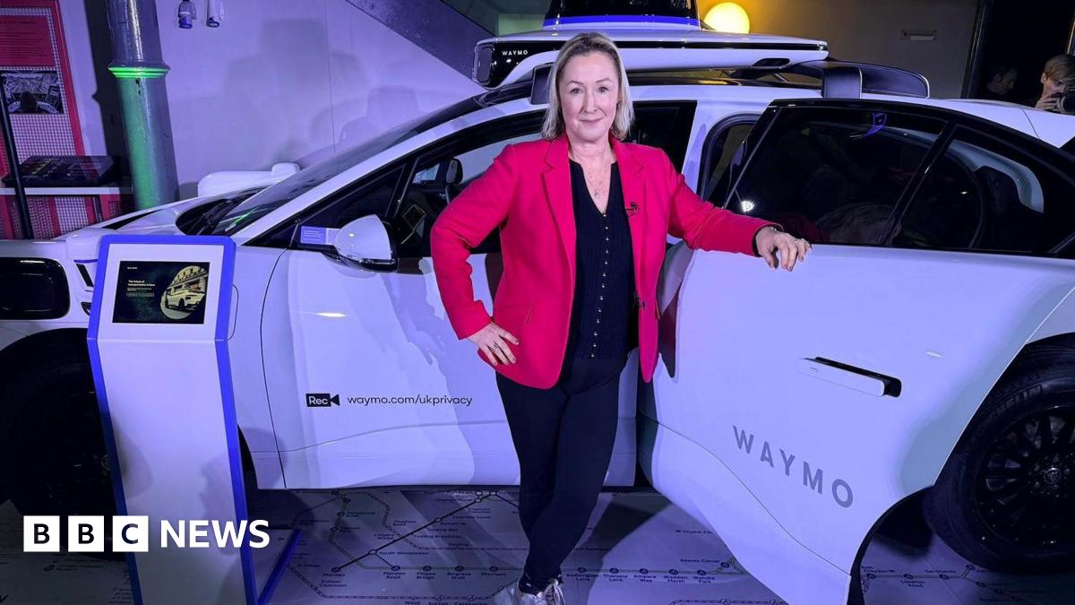 BBC technology editor Zoe Kleinman stands in front of a white car, wearing a red jacket over a black top and black trousers