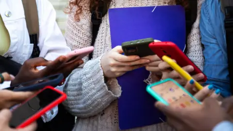 Getty Images Hands of teenage girls on mobile phones