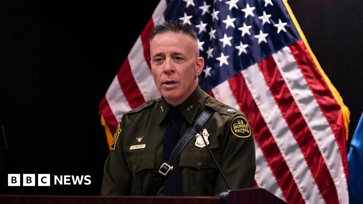 Jacqui Furneaux sitting on her motorbike smiling outside a rundown house on her travels in India