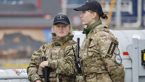 Getty Images Two female members of the Royal Danish Navy stand guard on a warship in Nuuk, Greenland.