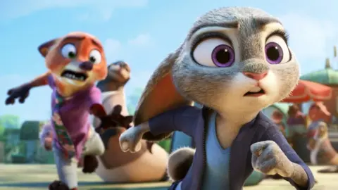 Disney The rabbit police officer (voiced by Ginnifer Goodwin) and con artist fox (Jason Bateman) seen running in a still from the film Zootopia 2, also known as Zootropolis 2