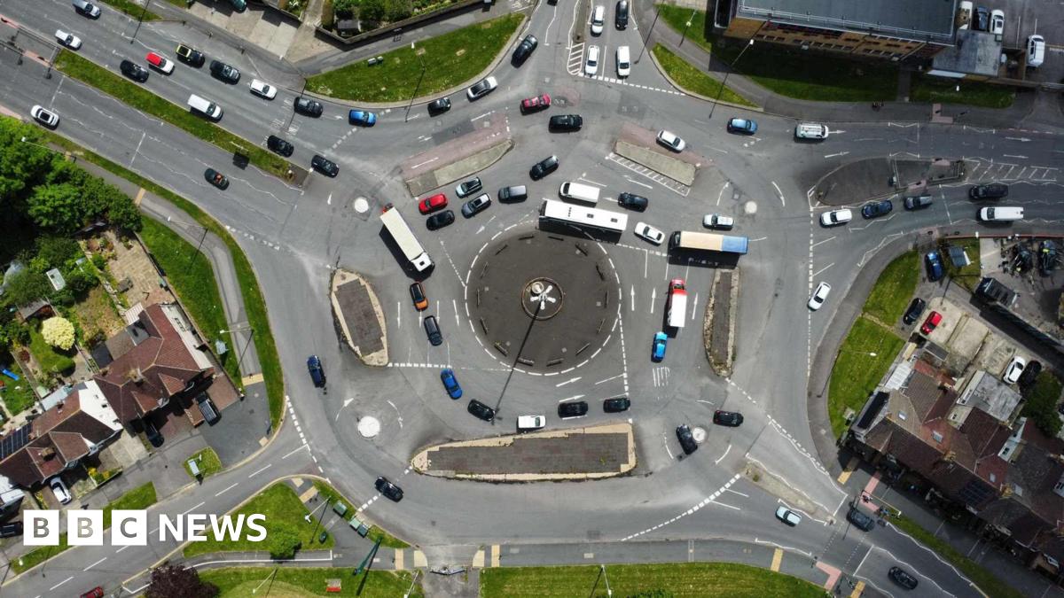 An aerial view of Swindon's magic roundabout, with cars, buses and other vehicles travelling around it.