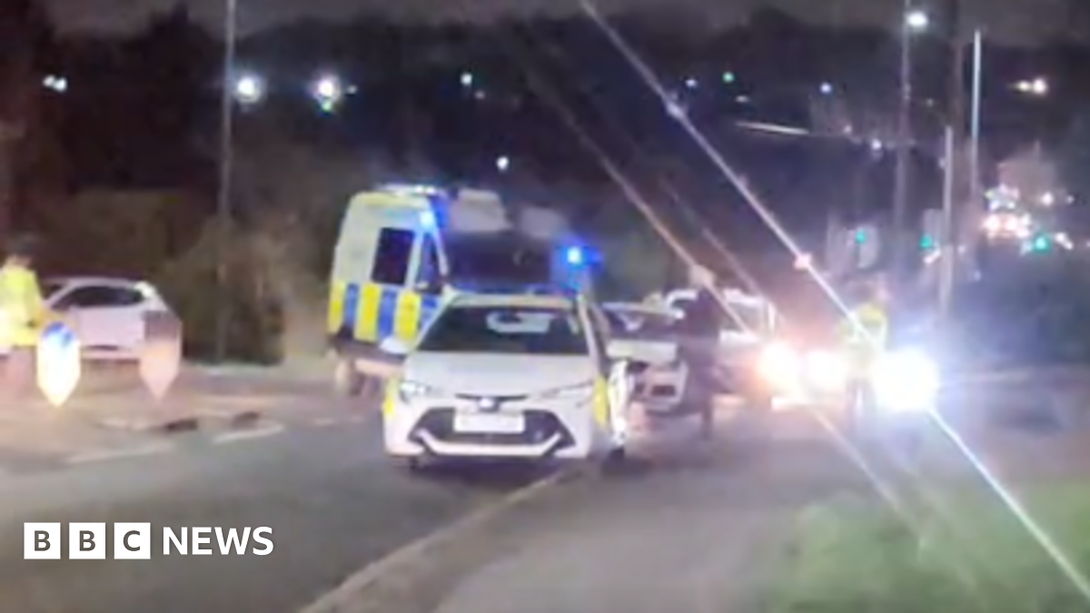 An image of the police scene, with flashing lights and various police and ambulance vehicles