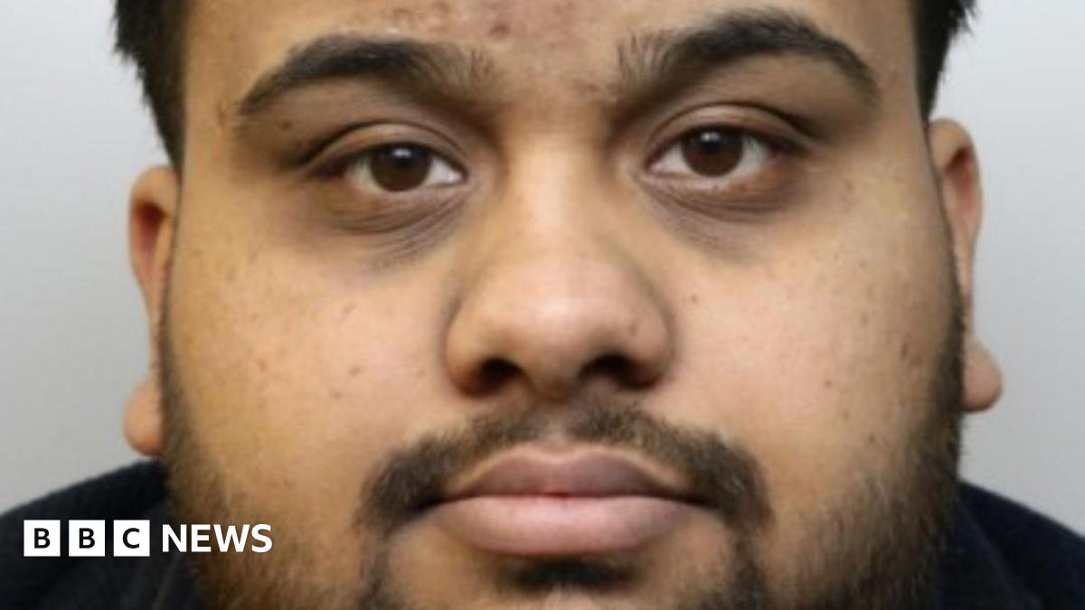 A police-issued photograph of Ahmed, he has short dark hair and a shor beard. He wears a black T-shirt.