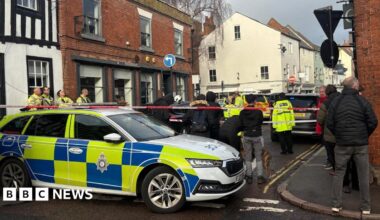 A police car with people in front of a cordon