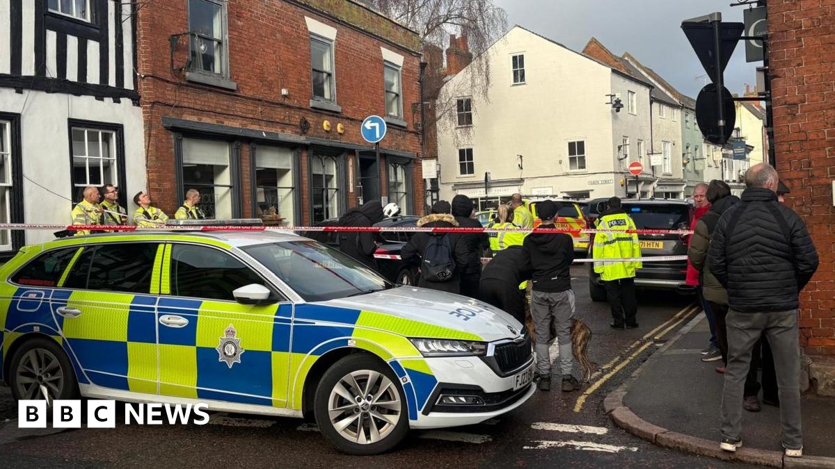 A police car with people in front of a cordon