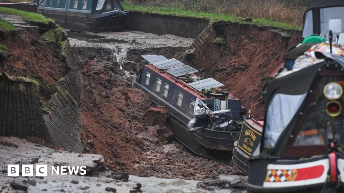 A photo showing the canal breach with one boat at the bottom of the sinkhole and another teetering on the edge.