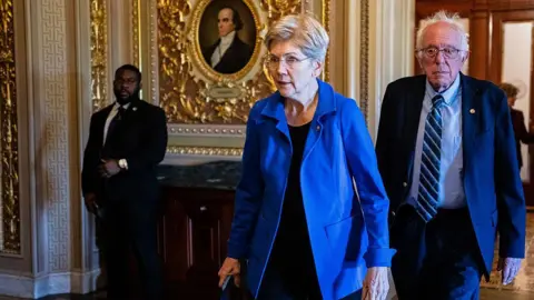 Bloomberg via Getty Images A woman wearing a blue jacket and a man wearing a suit walk through the US Capitol.