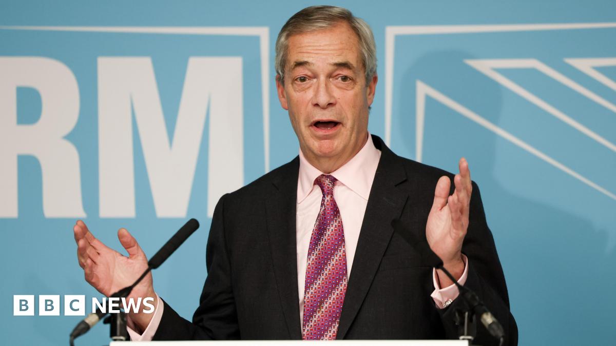 Nigel Farage speaks into a microphone in front of a turquoise background during a press conference