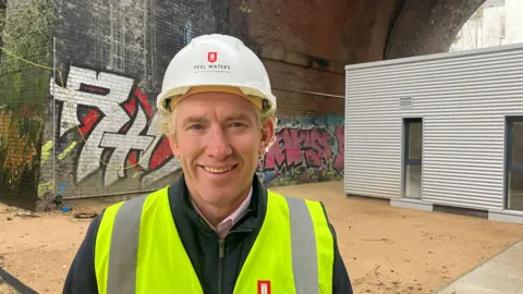 Photograph of James Whittaker from the property firm Peel Waters. He is pictured beneath a railway arch at the Embassy Homeless Village in Castlefield.
