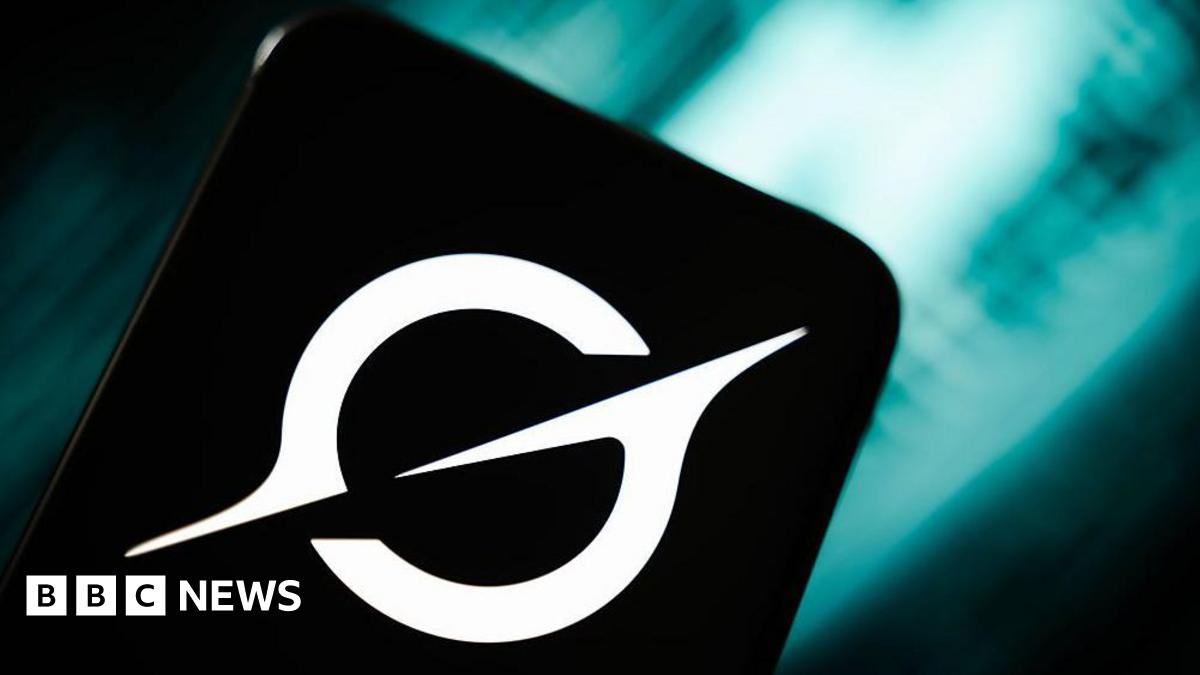 An image of the Grok logo on a smartphone in front of a teal coloured blurred abstract background