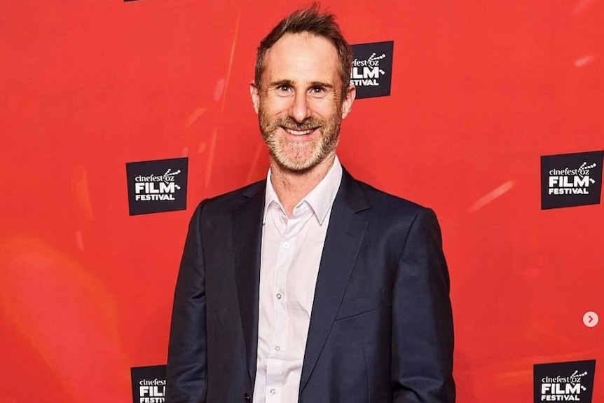 Craig Silvey pictured against a red background imprinted with the CinefestOZ film festival logo