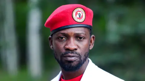 Getty Images Bobi Wine looks directly at the camera wearing a red beret, a red t-shirt and a white blazer