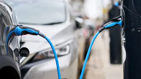 PA Media File photo of a Tesla car plugged into a Source London EV charging point in central London.