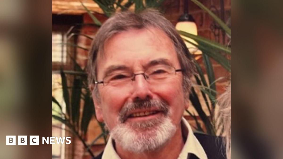 A picture of a smiling man with light brown hair, a grey goatee beard and rectangular glasses.