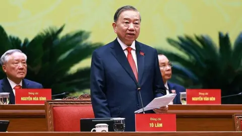 VIETNAM NEWS AGENCY/HANDOUT/EPA/Shutterstock To Lam is delivering a speech at a party session. He is wearing a suit and a red tie. 