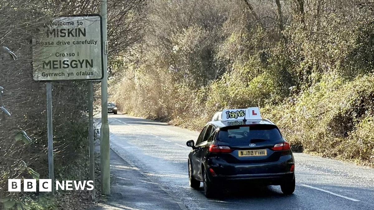 A learner driver is seen driving past a line of cars