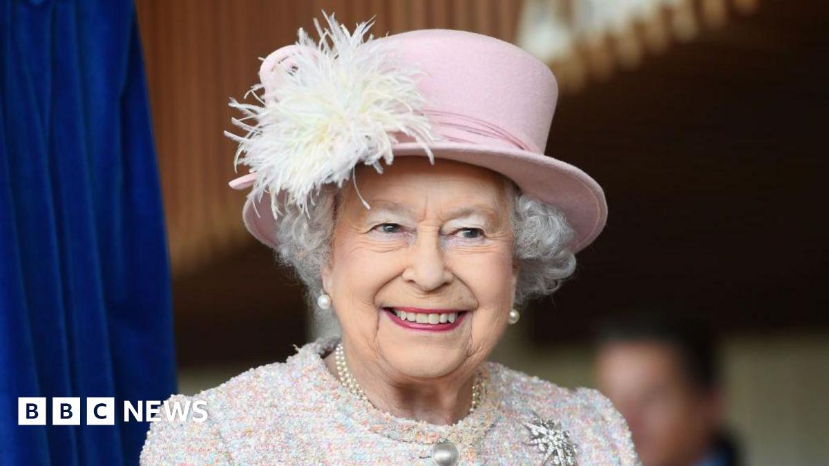Queen Elizabeth II is seen in a pink hat smiling during an appearance at the Chichester Theatre