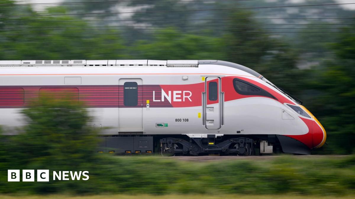 A white and red LNER train speeds through countryside