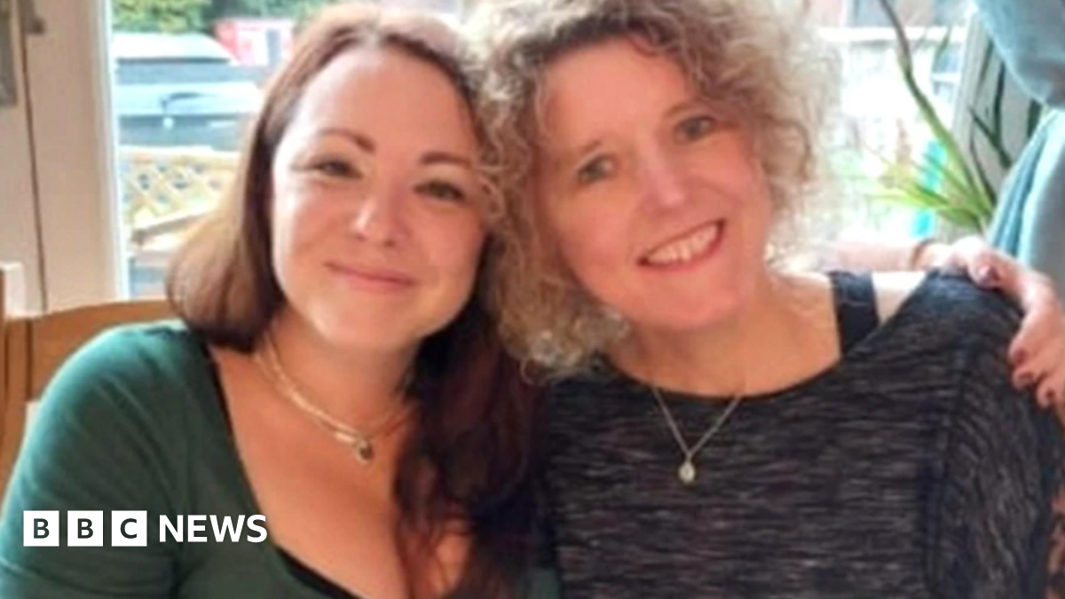 Helen and Rachael side by side smiling with their heads close together, with Helen's arm around Rachael's shoulder. One has curly blonde hair, and the other long dark hair.