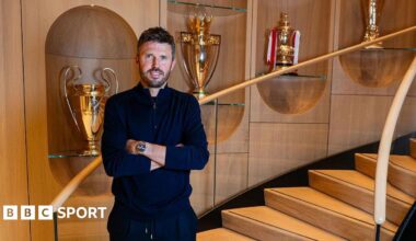 Image of Man United head coach Michael Carrick in front of trophies at Carrington Training Ground