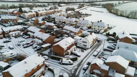 PA Media An aerial view of snow-covered houses in a village in Warwickshire, England