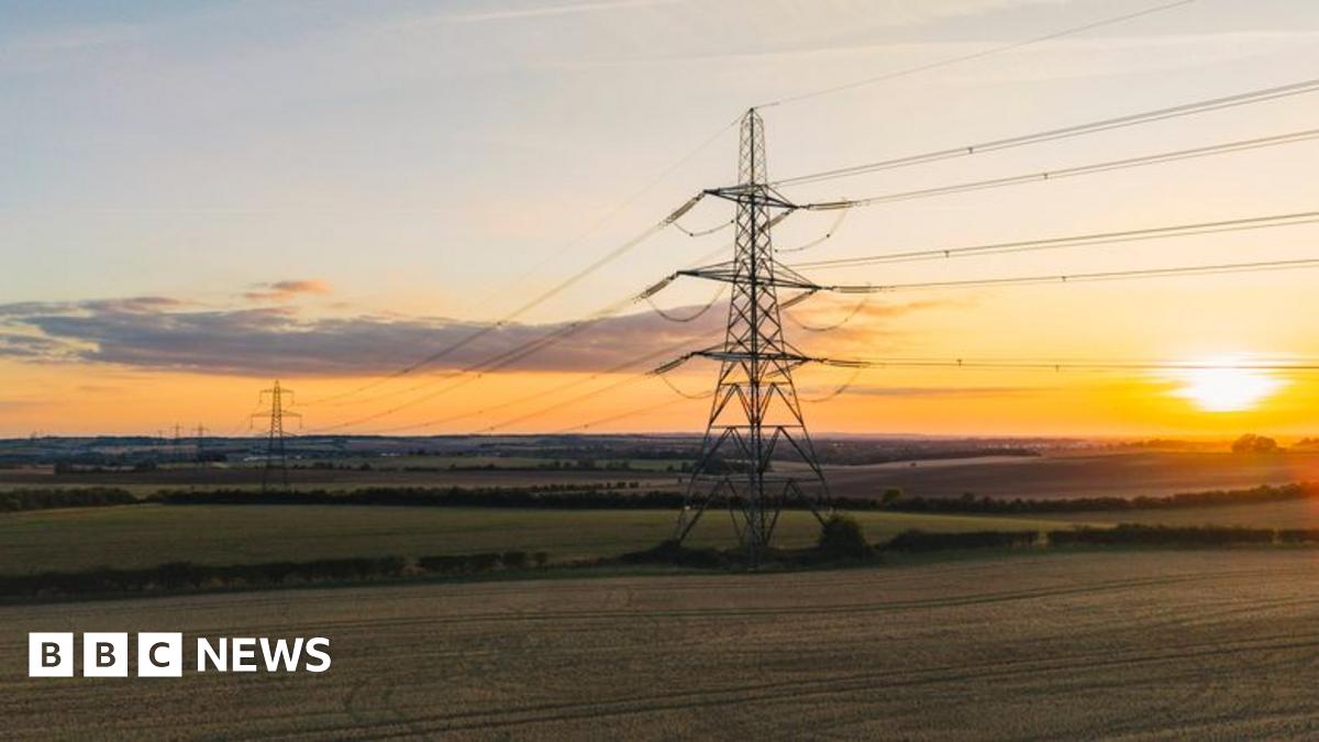 An elevated/drone view of an electricity pylon in the UK at sunset.