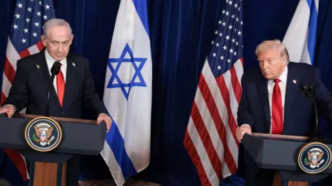 Reuters Trump and Netanyahu speaking at a conference, while both wearing suits with red ties with Israeli and US flags in background