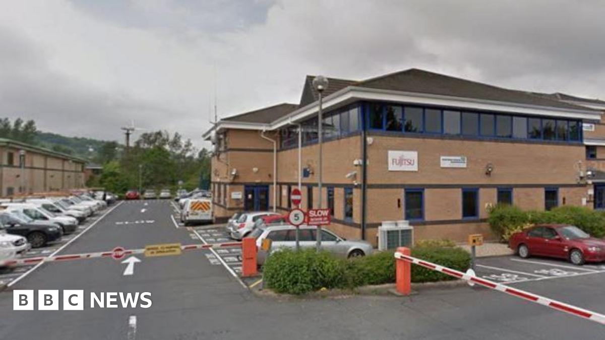 Brown brick office building with car park and barrier in front