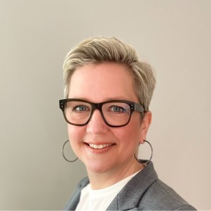 Head shot of a smiling woman with short blonde hair and black glasses