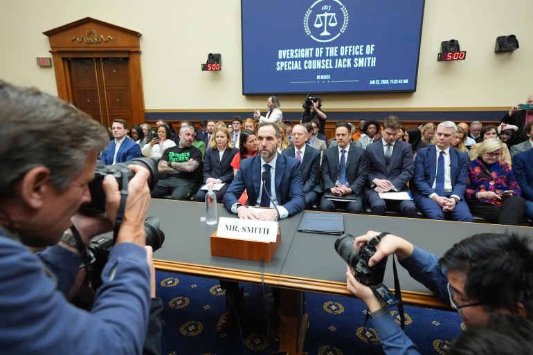 A photographer snaps a shot of Jack Smith at a committee meeting.