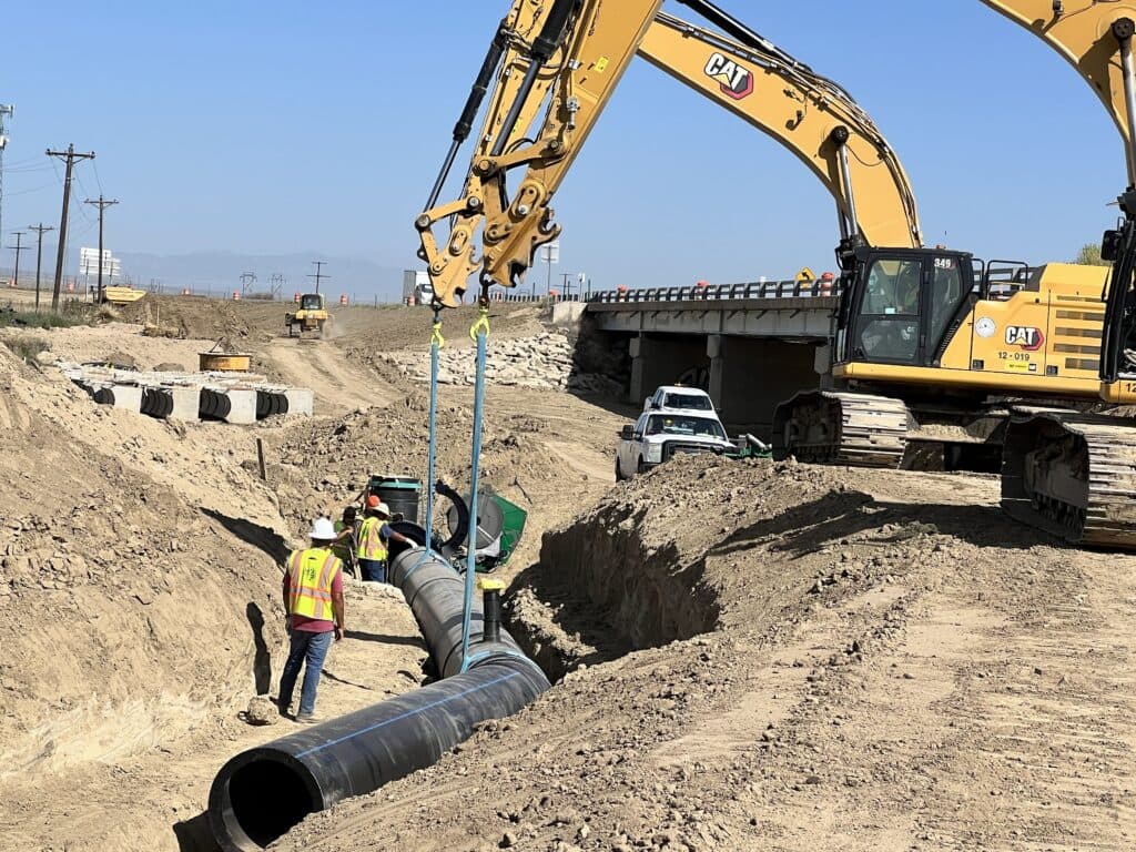 heavy equipment and workers install a pipeline