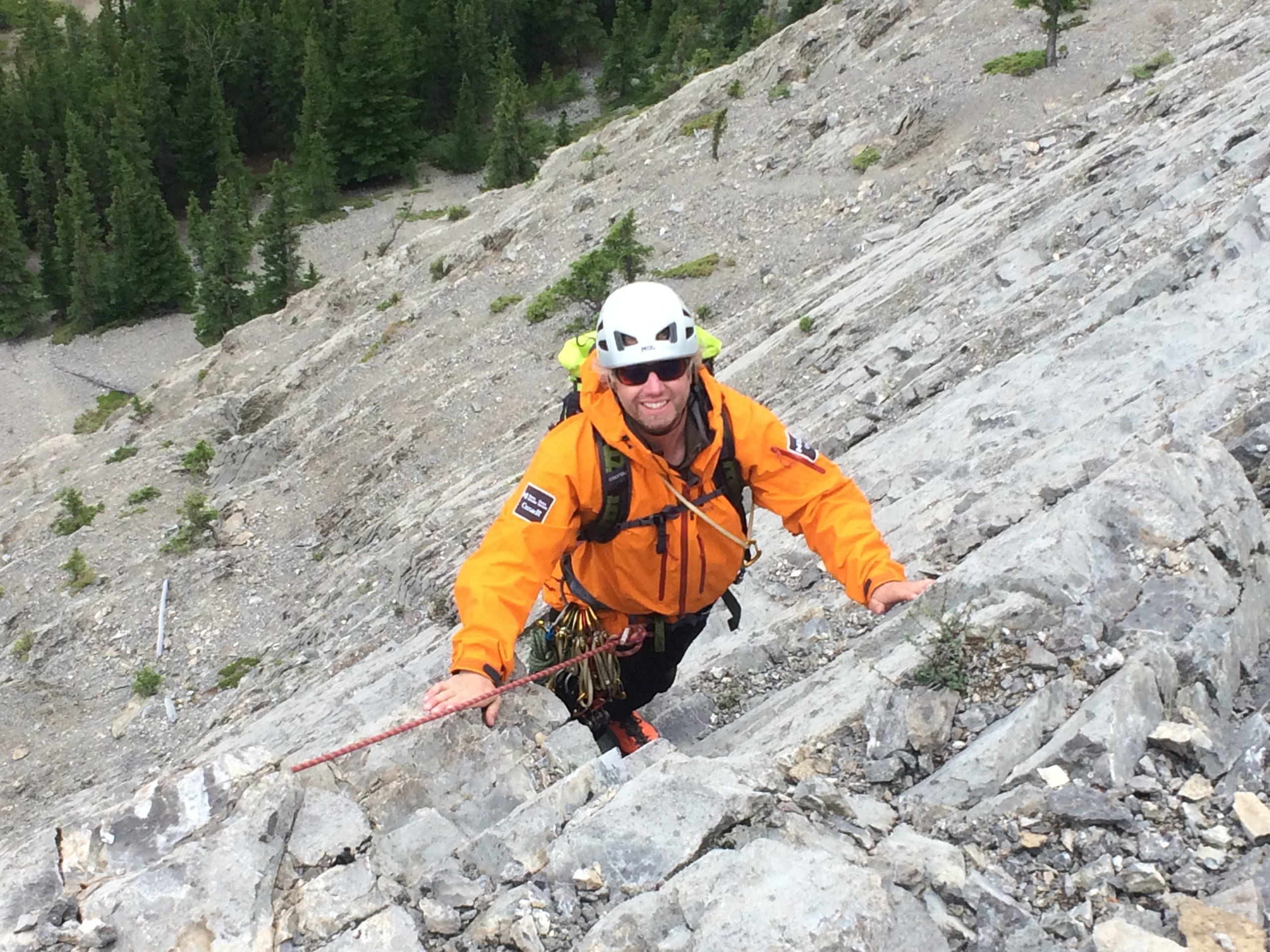 Mountain guide Jordy Shepherd looks up as he climbs a rock face.