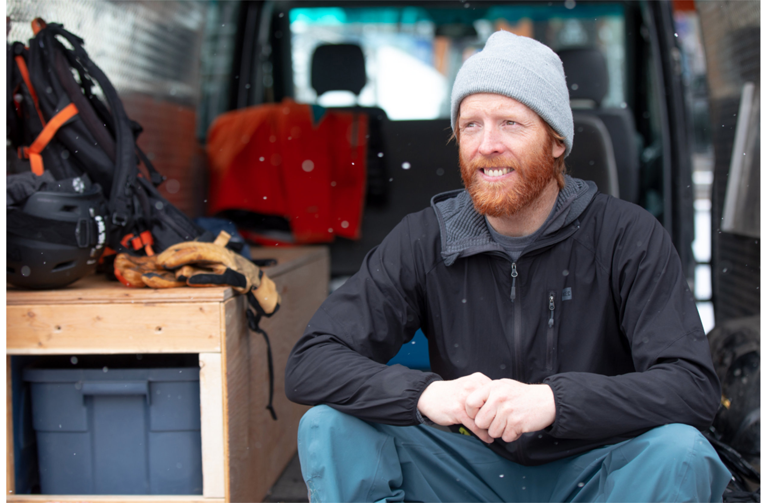 Alpine guide Kevin Hjertaas sits on the back of a van loaded with gear.