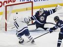 Maple Leafs' Max Domi scores the game-winning overtime goal against  Jets goaltender Connor Hellebuyck in Winnipeg on Saturday, January 17, 2026. 