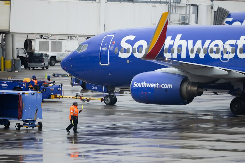 Airport workers direct a Southwest Airline plane as rain falls at Dallas Love Field Airport...