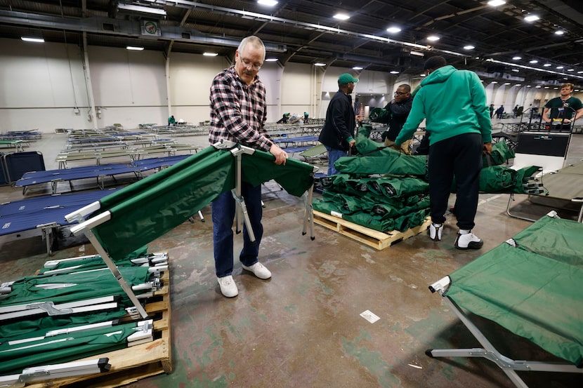 Volunteer Don Carey, 61 of Richardson, left, sets up a stretcher at the inclement weather...