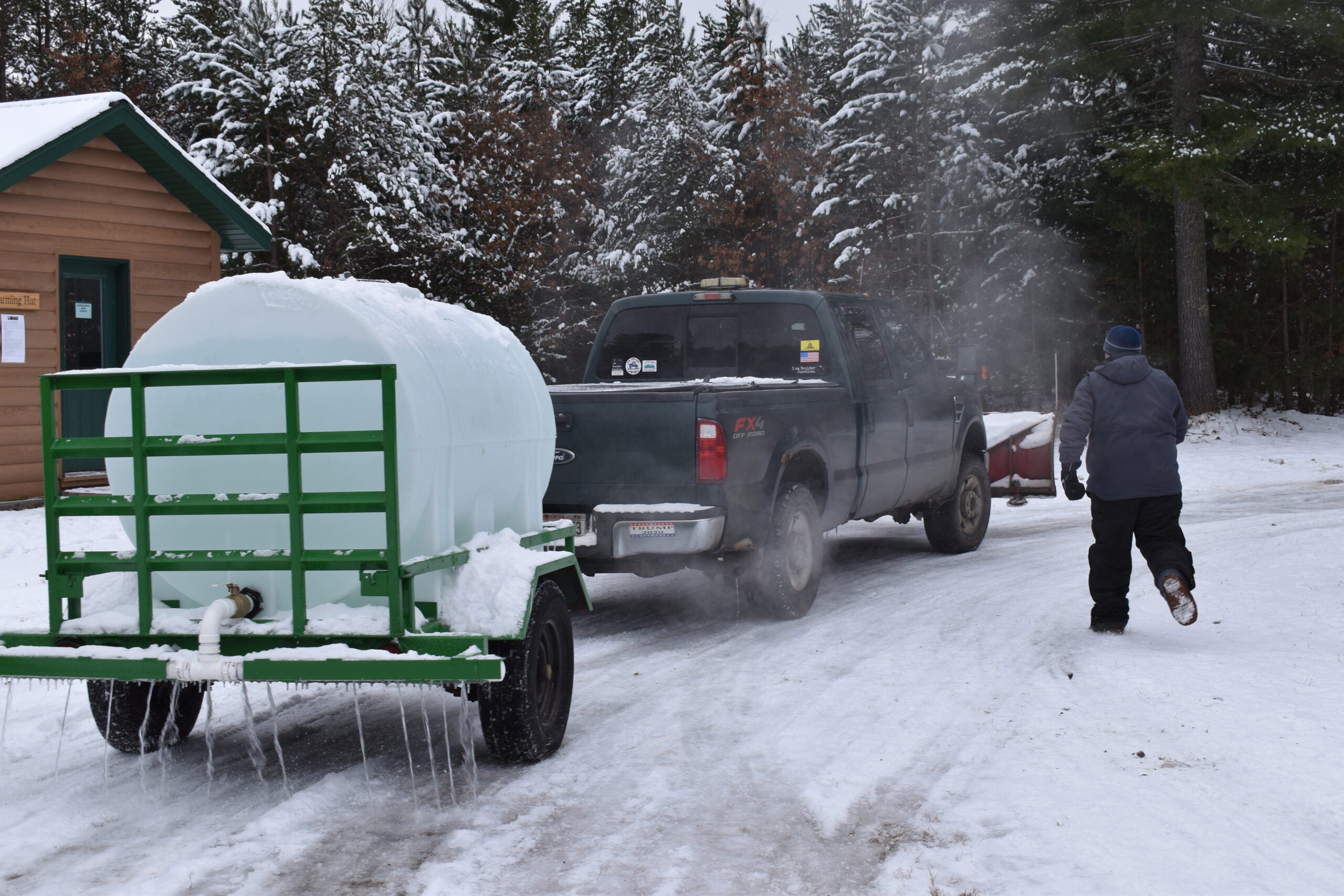 Volunteer Steve Weber trails a truck pulling a water tank that is putting down water for the 0.8-mile-long ice skating trail in Boulder Junction.